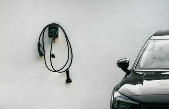 Sc&egrave;ne ext&eacute;rieure urbaine avec v&eacute;hicule &eacute;lectrique BMW i3 argent&eacute; en charge via borne de recharge publique
