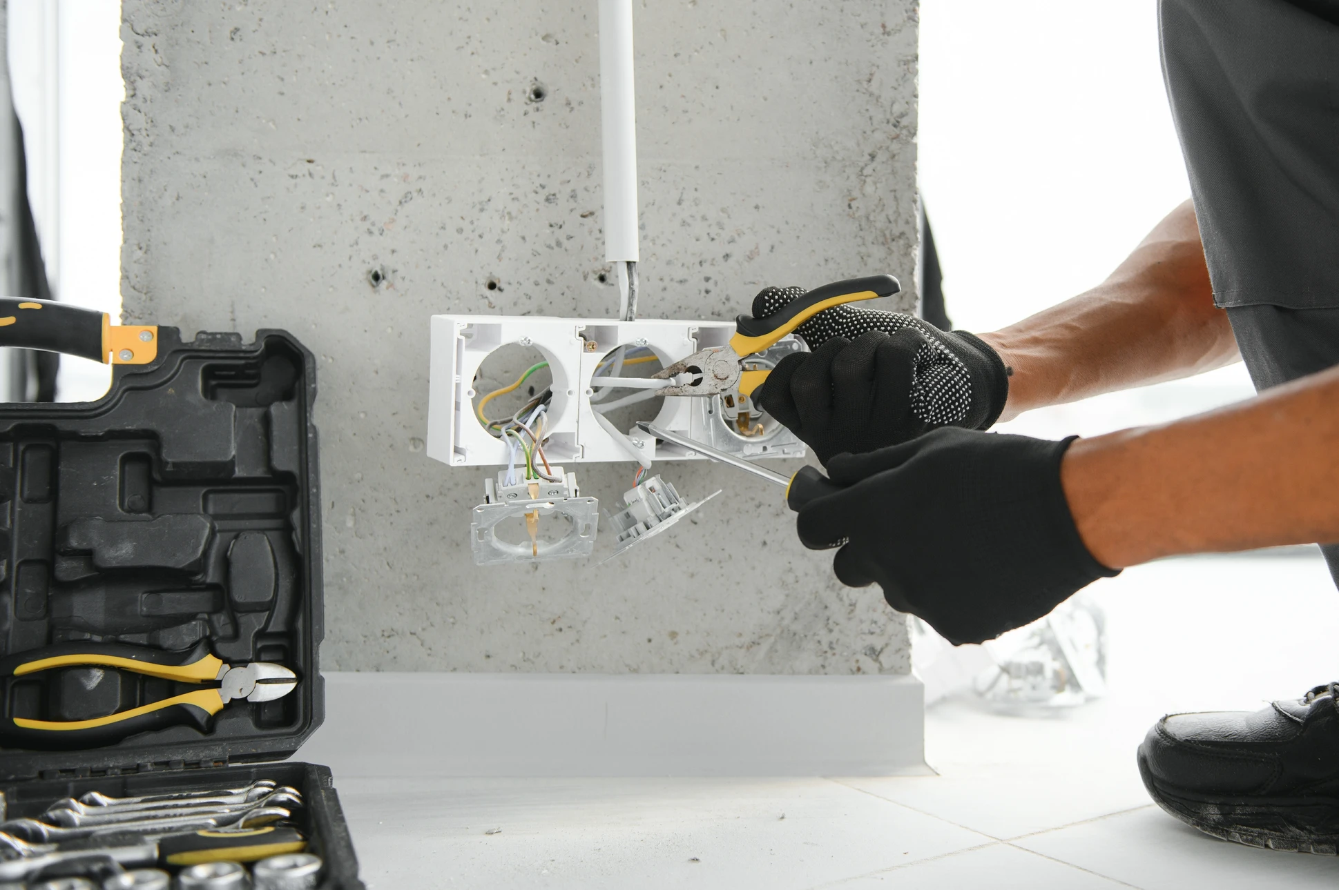 Un électricien travaille sur une installation électrique murale dans un intérieur résidentiel