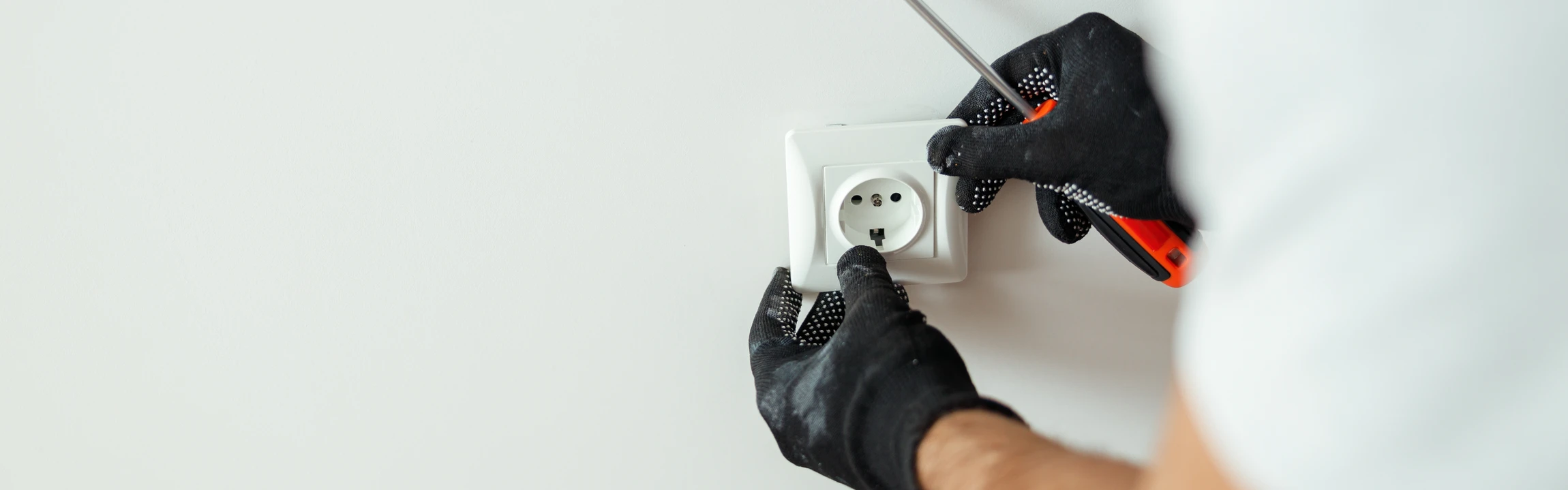 Un électricien installe une prise électrique murale blanche dans un intérieur moderne