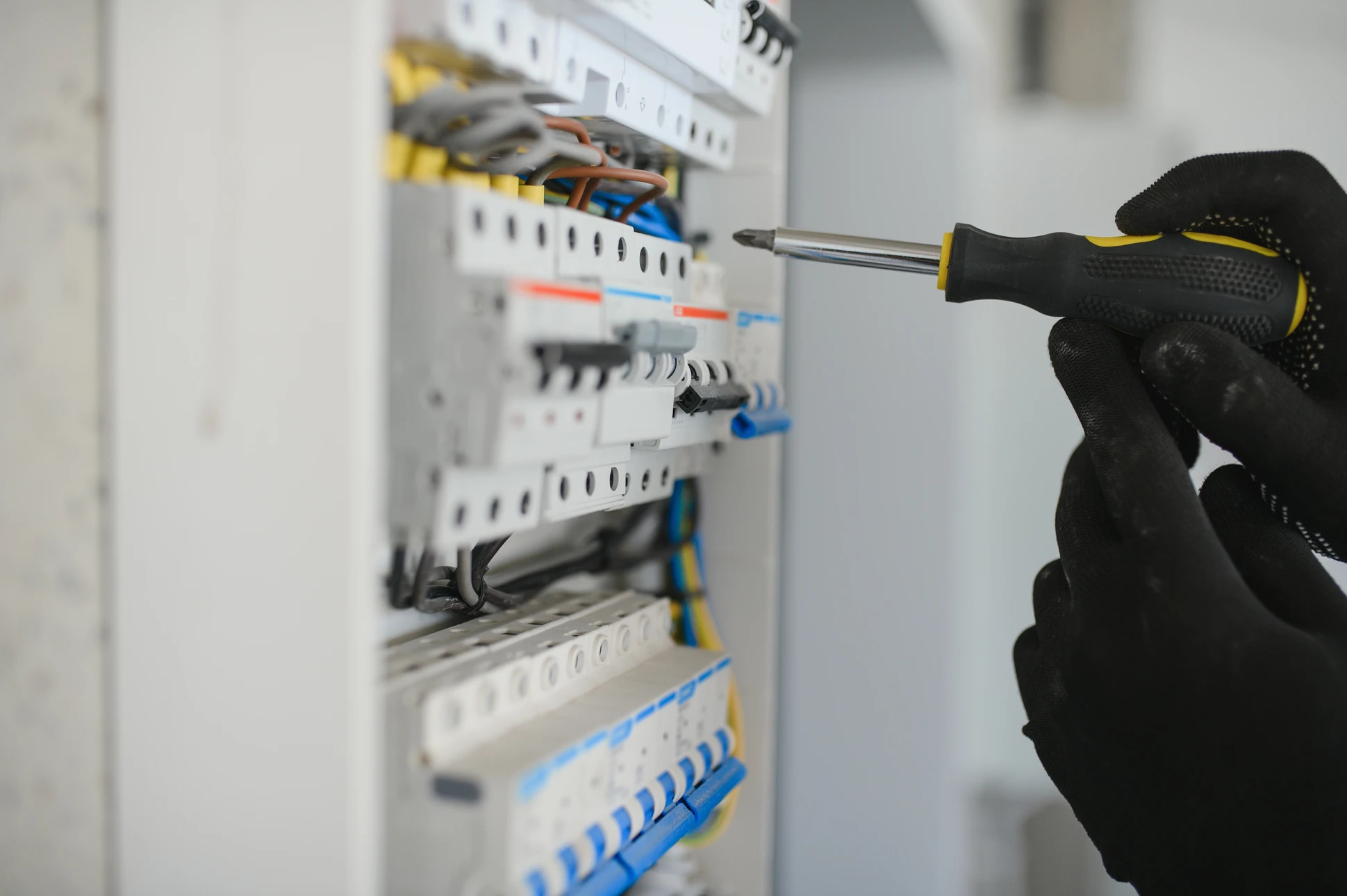 Intérieur d'armoire électrique avec technicien effectuant maintenance sur tableau de distribution