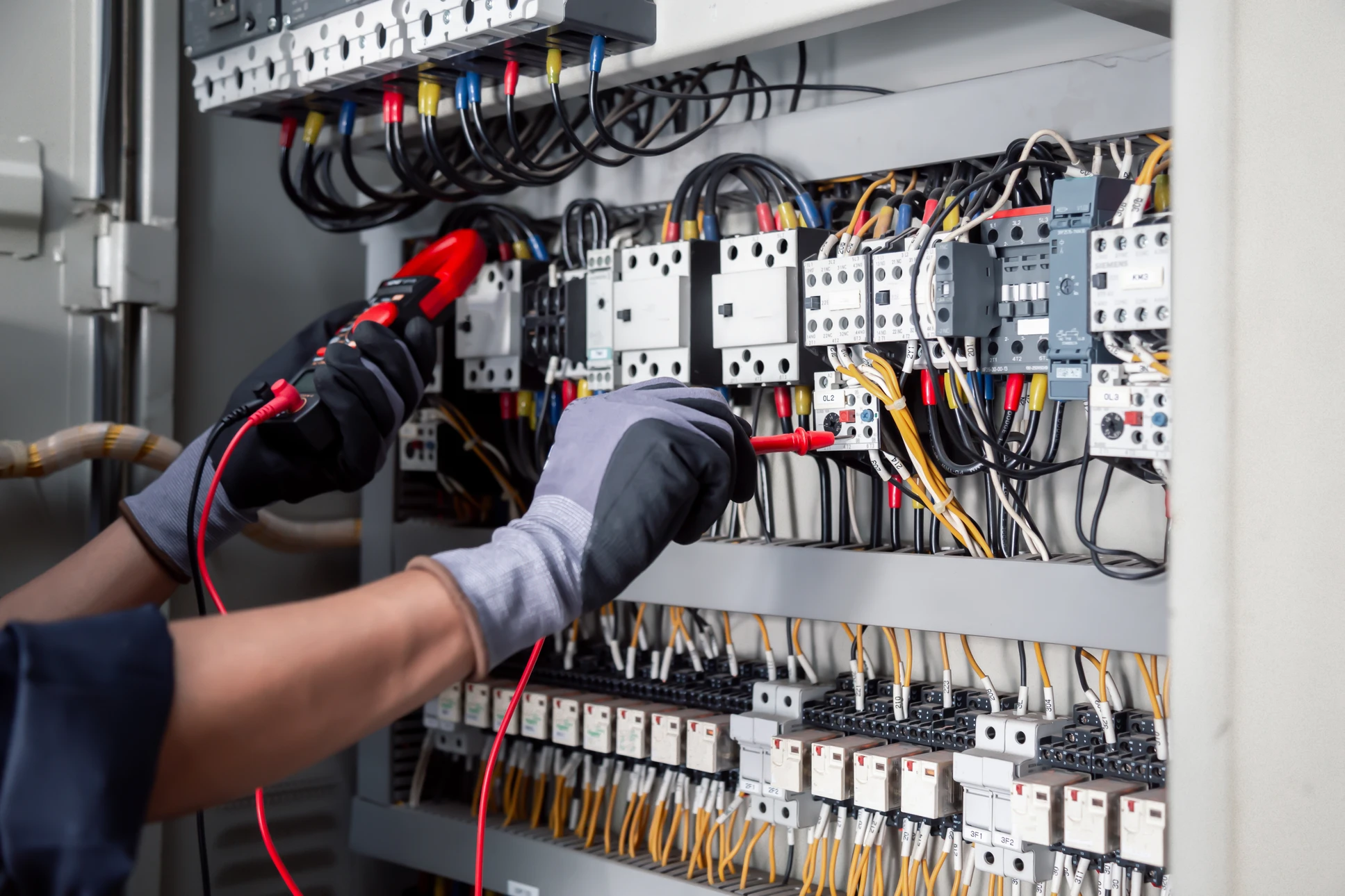 Électricien professionnel en casque de sécurité blanc travaillant dans un tableau électrique industriel