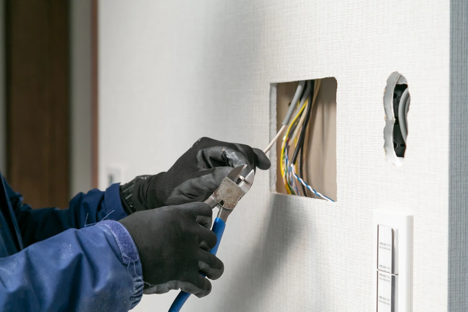 Électricien en équipement de protection individuelle travaillant sur installation électrique intérieure